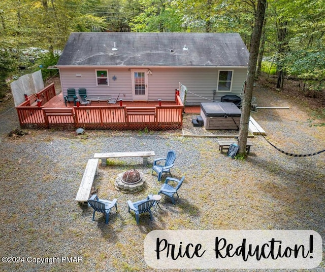 rear view of property featuring an outdoor fire pit, a wooden deck, and a hot tub