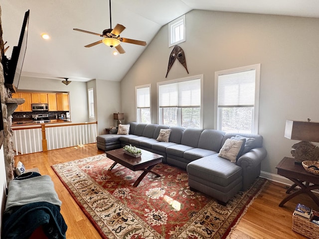 living room with high vaulted ceiling, ceiling fan, and light wood-style flooring