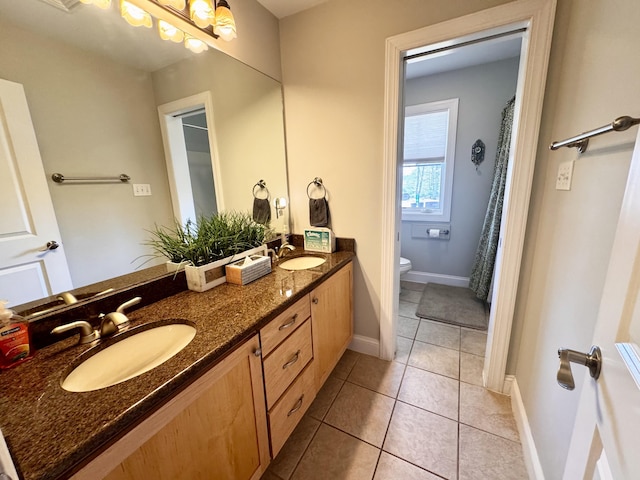 full bathroom featuring double vanity, a sink, tile patterned flooring, and toilet