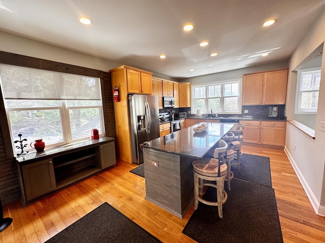 kitchen with a breakfast bar, a sink, a center island, stainless steel appliances, and decorative backsplash