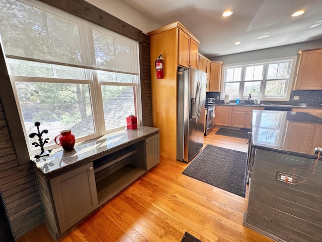 kitchen with dark stone countertops, recessed lighting, a sink, light wood-style flooring, and appliances with stainless steel finishes