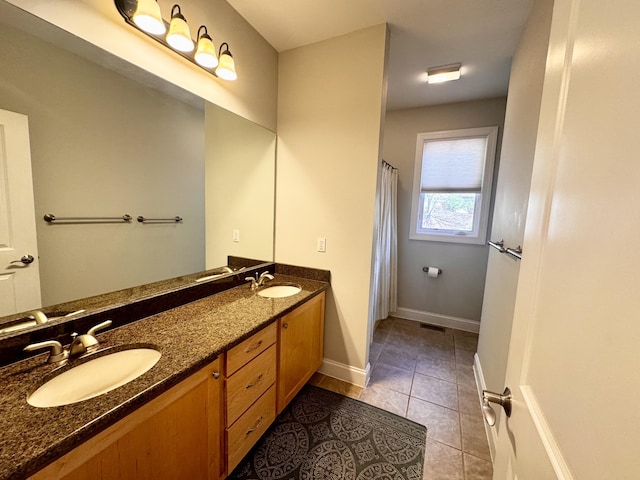 bathroom with baseboards, double vanity, tile patterned floors, and a sink