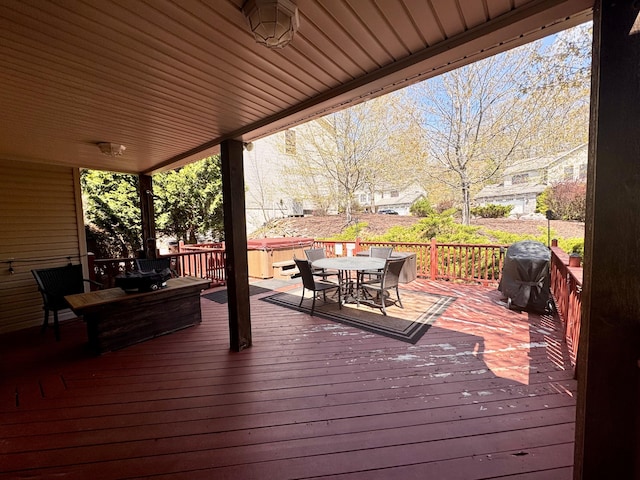 deck with outdoor dining area, a hot tub, and a grill