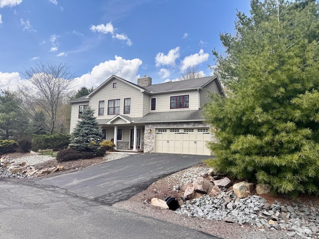 view of front facade with a porch, a chimney, an attached garage, and driveway