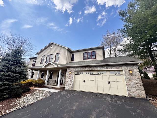 traditional-style home featuring a porch, driveway, and stone siding