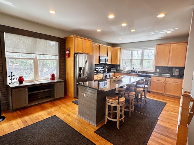 kitchen featuring appliances with stainless steel finishes, a kitchen island, a breakfast bar area, and backsplash