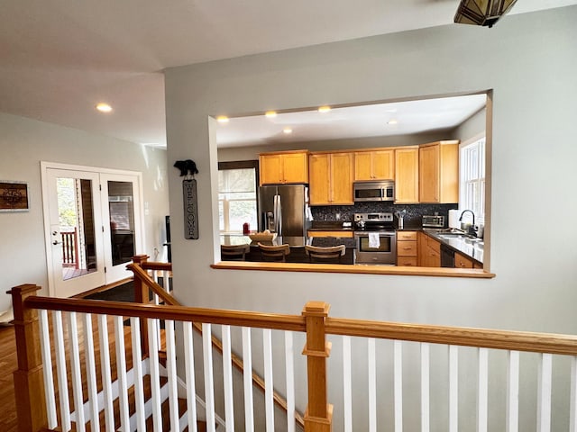 kitchen with dark countertops, appliances with stainless steel finishes, a sink, recessed lighting, and decorative backsplash