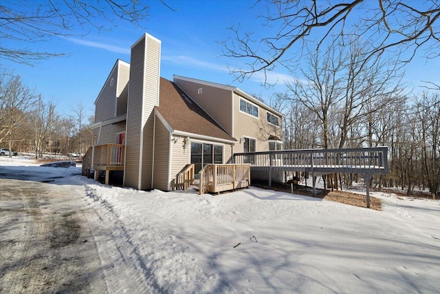 snow covered property with a deck and a chimney