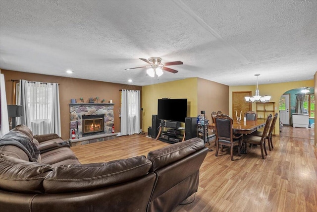 2726 Pocono Cir, Bartonsville, PA 18321 - living area with light wood finished floors, a textured ceiling, ceiling fan, a stone fireplace, and arched walkways