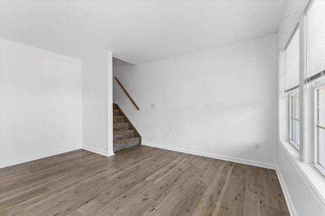 unfurnished room with stairway, baseboards, and wood finished floors