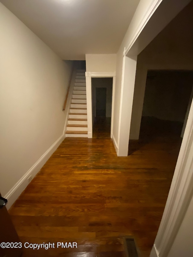 hall with stairway, wood finished floors, and baseboards