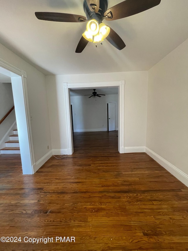 empty room with stairs, baseboards, and wood finished floors