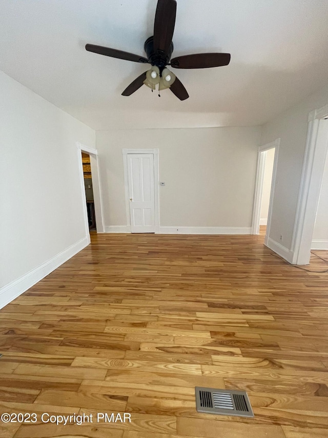 unfurnished room featuring ceiling fan, light wood-type flooring, visible vents, and baseboards