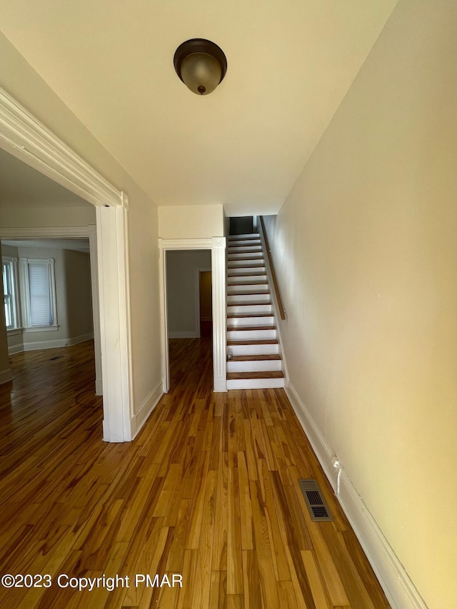 interior space featuring visible vents, stairway, baseboards, and wood finished floors