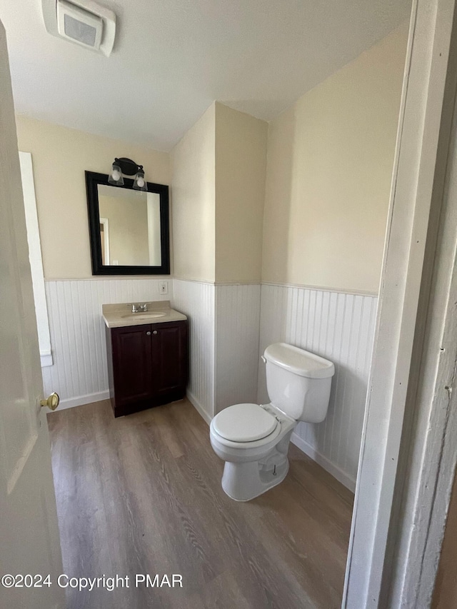 bathroom featuring visible vents, toilet, a wainscoted wall, wood finished floors, and vanity