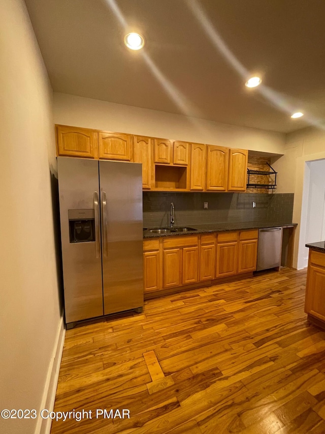 kitchen featuring open shelves, stainless steel appliances, a sink, and wood finished floors