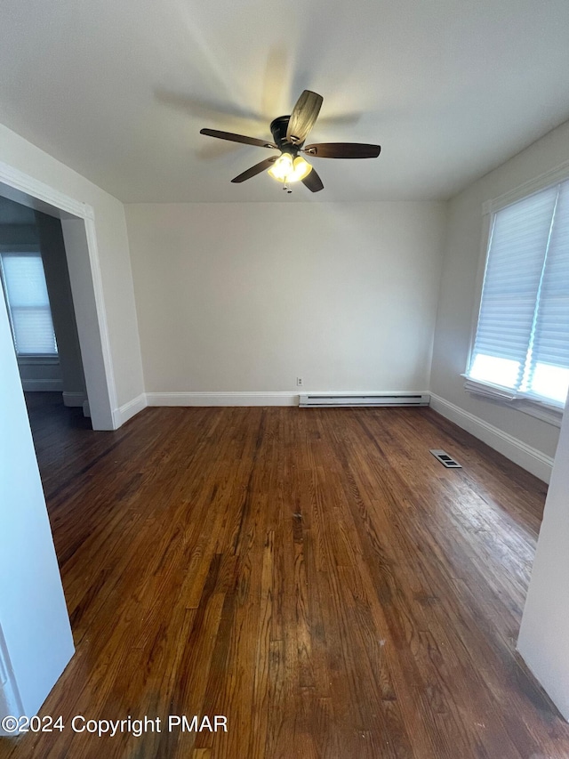 spare room with dark wood-style floors, baseboard heating, visible vents, and baseboards