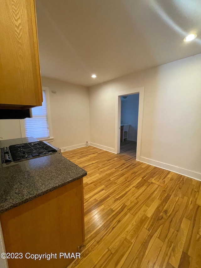 kitchen with light wood-style floors, baseboards, dark stone counters, and recessed lighting