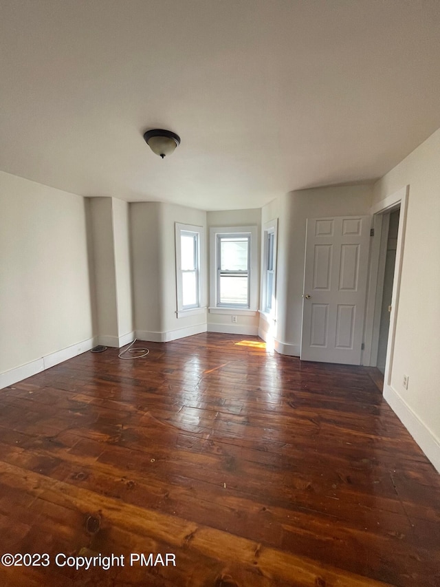 unfurnished room featuring wood-type flooring and baseboards