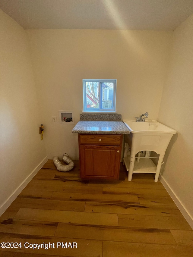 laundry room with cabinet space, baseboards, light wood-style flooring, hookup for a washing machine, and a sink