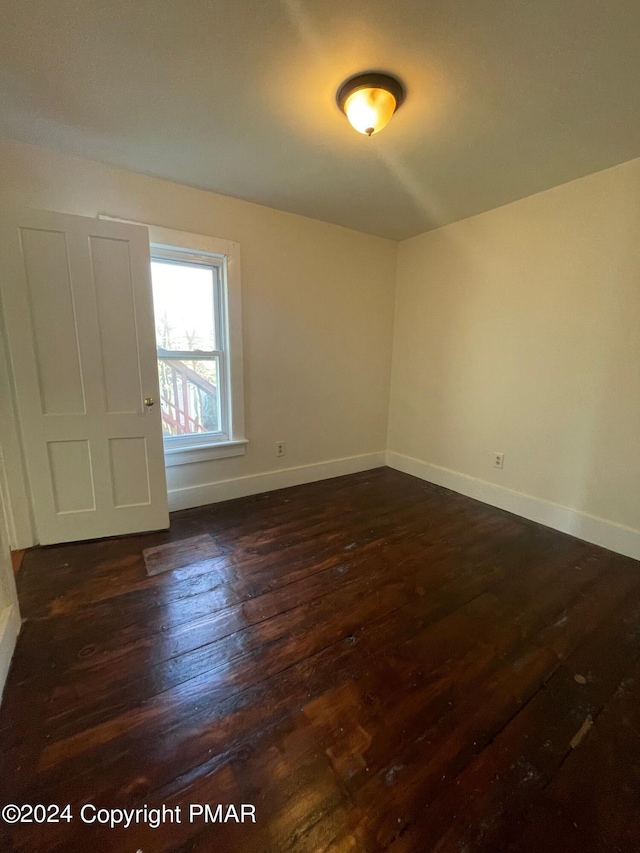 unfurnished room featuring dark wood-type flooring and baseboards