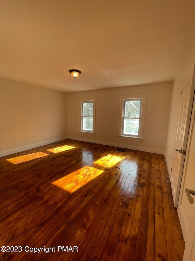 empty room with wood-type flooring and baseboards