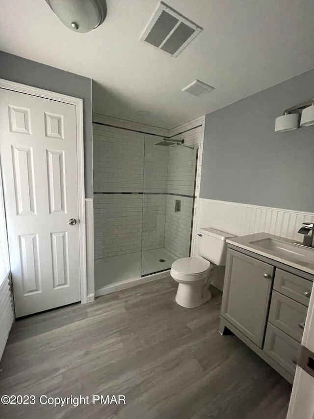 bathroom with toilet, a stall shower, wood finished floors, and visible vents