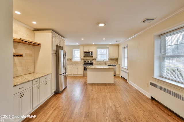 kitchen with radiator, visible vents, light wood finished floors, a sink, and appliances with stainless steel finishes
