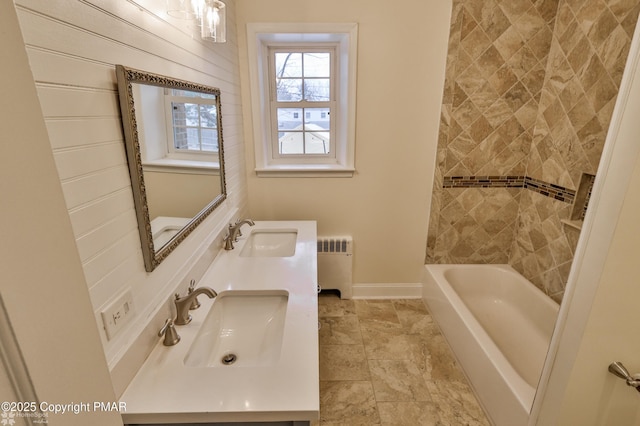 full bath with a sink, baseboards, radiator, and double vanity