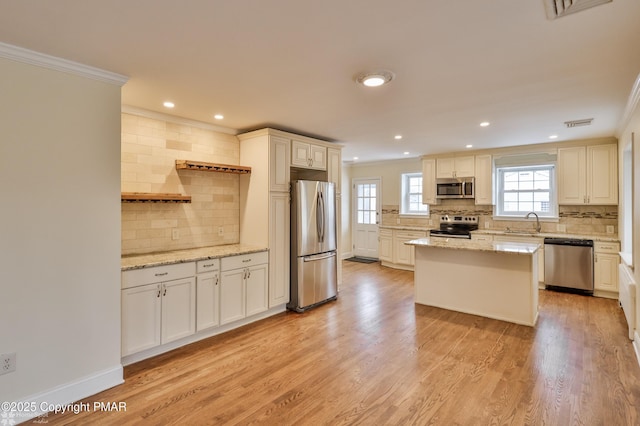 kitchen with visible vents, light wood-style flooring, ornamental molding, a sink, and appliances with stainless steel finishes