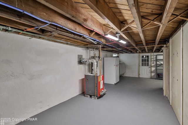 unfinished basement with freestanding refrigerator