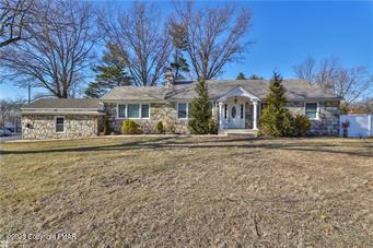 single story home featuring stone siding and a front yard