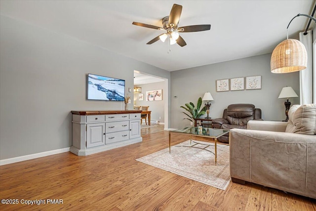 living room featuring light wood finished floors, ceiling fan, and baseboards