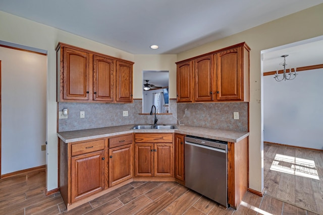 kitchen with brown cabinetry, a sink, wood tiled floor, and stainless steel dishwasher