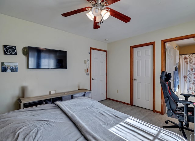 bedroom with a ceiling fan, wood finished floors, and baseboards