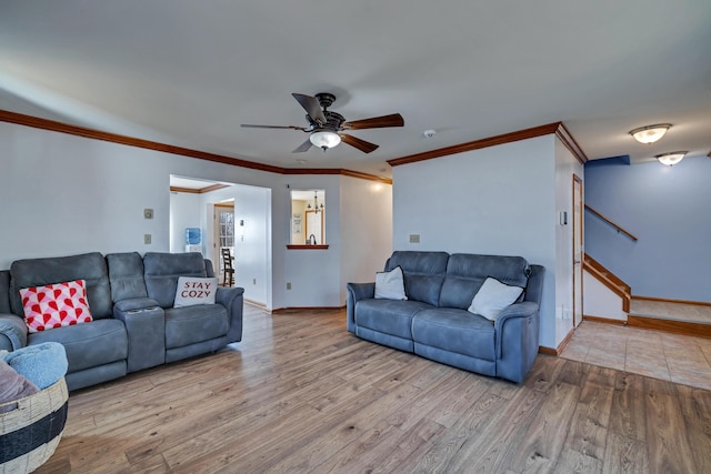 living area featuring a ceiling fan, stairs, baseboards, and wood finished floors