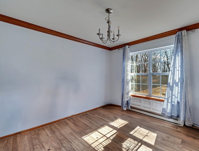 unfurnished room with baseboards, an inviting chandelier, wood finished floors, and crown molding