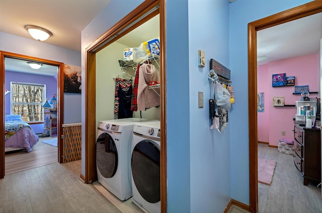 laundry area featuring light wood-type flooring, baseboards, laundry area, and washer and clothes dryer