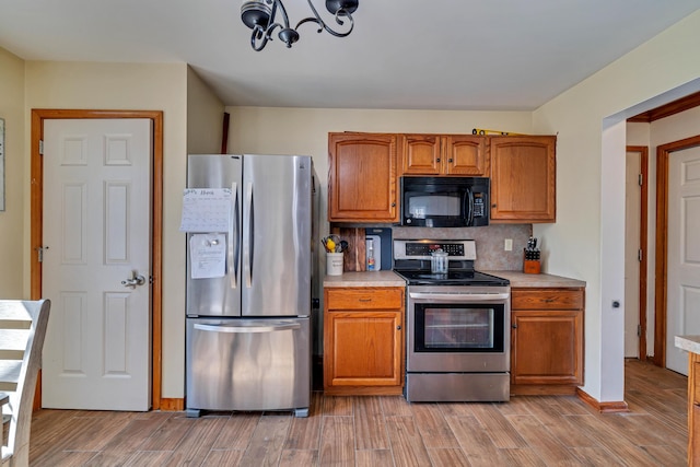 kitchen with light countertops, tasteful backsplash, appliances with stainless steel finishes, and light wood-type flooring