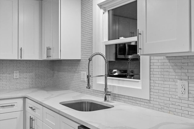 173 Water View Dr, Hawley, PA 18428 - kitchen featuring stainless steel microwave, white cabinets, tasteful backsplash, and light stone counters