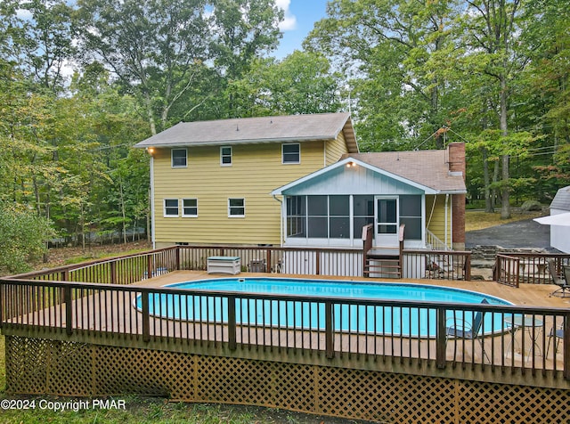 view of swimming pool with a fenced in pool, a sunroom, and a wooden deck