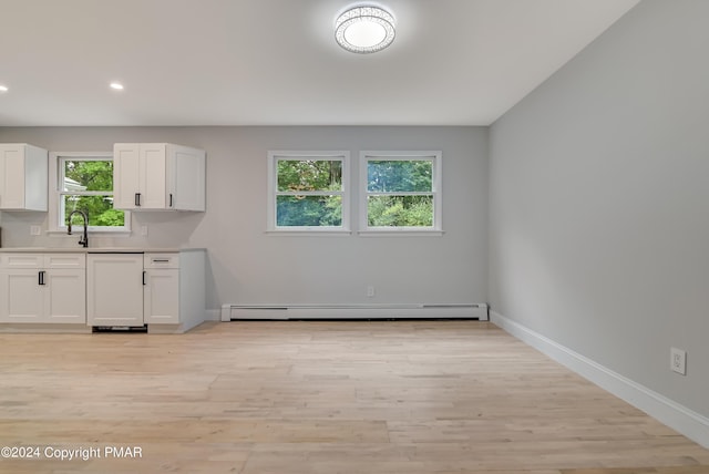 kitchen featuring baseboards, white cabinets, baseboard heating, light countertops, and light wood-type flooring