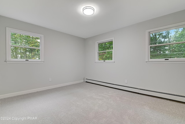 spare room featuring a baseboard heating unit, a healthy amount of sunlight, and carpet flooring