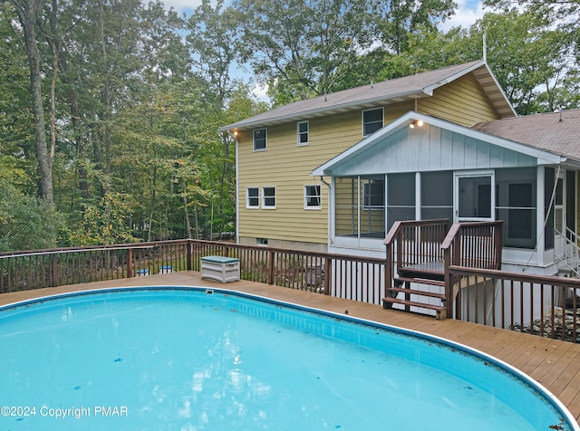 view of swimming pool with a fenced in pool, a sunroom, and a wooden deck