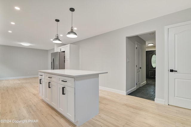 kitchen with stainless steel fridge, baseboards, white cabinets, light countertops, and light wood-style floors