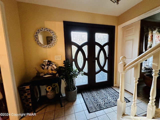 tiled foyer entrance featuring french doors, a healthy amount of sunlight, and stairway