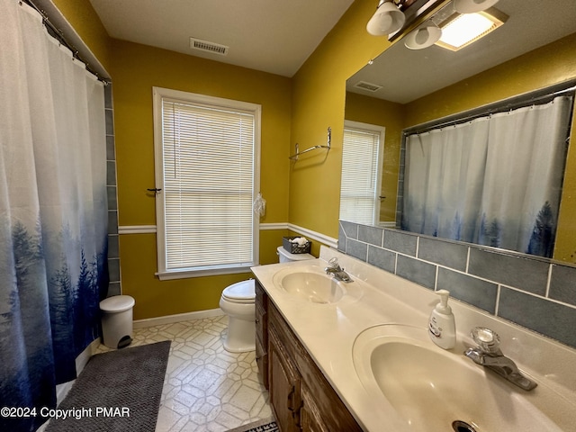 bathroom featuring toilet, visible vents, backsplash, and a sink