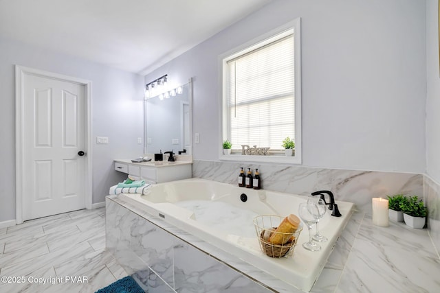 bathroom with marble finish floor, a tub with marble appearance, and vanity