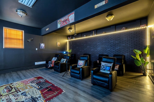 home theater featuring brick wall and wood finished floors