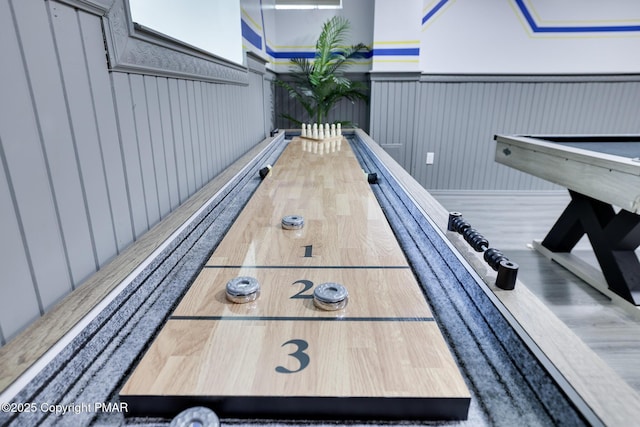 game room with a bowling alley and wooden walls